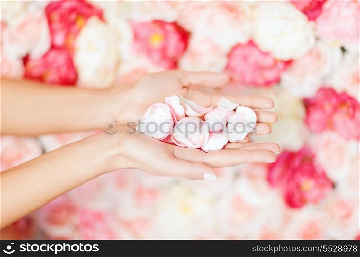 health and beauty concept - close up of womans cupped hands with flower petals