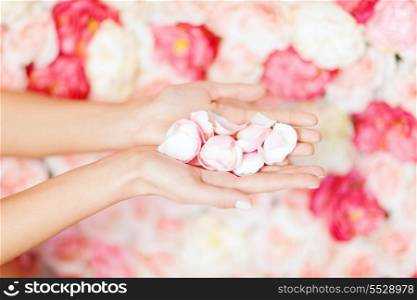 health and beauty concept - close up of womans cupped hands with flower petals