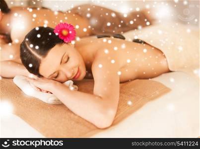 health and beauty concept - couple in spa salon with hot stones