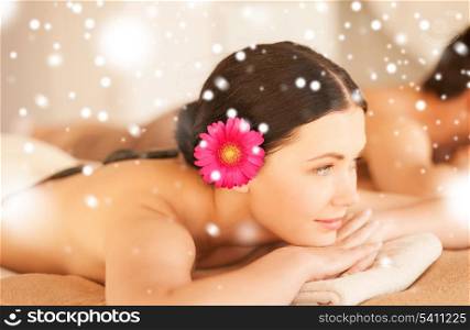 health and beauty concept - couple in spa salon with hot stones