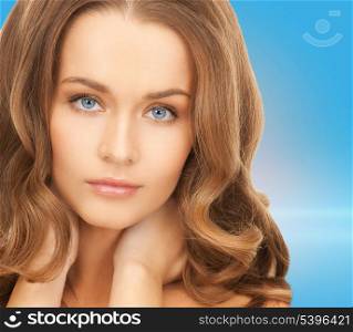 health and beauty concept - face and hands of beautiful woman with long hair over blue background