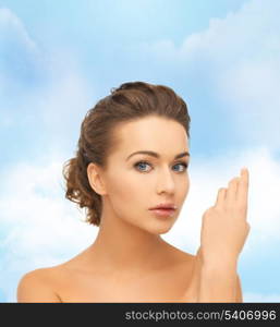 health and beauty concept - face and hands of beautiful woman with updo