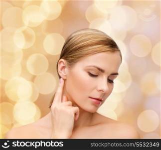 health and beauty concept - face of beautiful woman touching her ear
