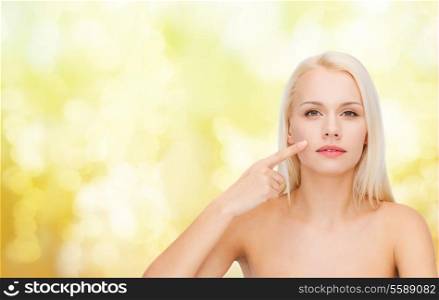 health and beauty concept - face of beautiful young woman pointing at her cheek