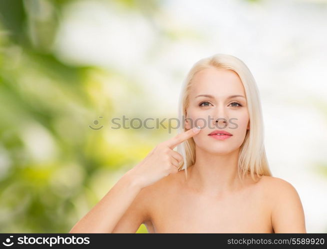 health and beauty concept - face of beautiful young woman pointing at her cheek