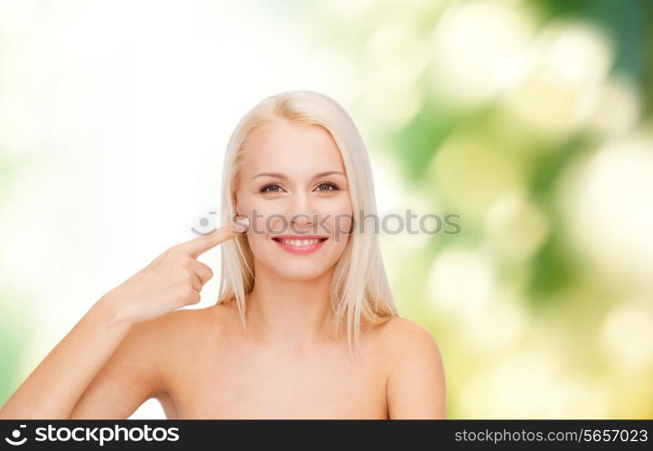 health and beauty concept - face of beautiful young woman pointing at her cheek