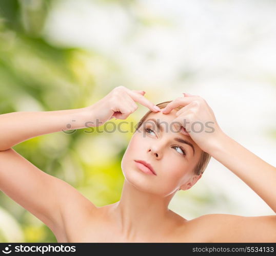 health and beauty concept - face of beautiful young woman squeezing acne spots