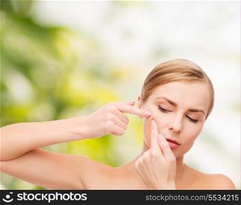 health and beauty concept - face of beautiful young woman squeezing acne spots