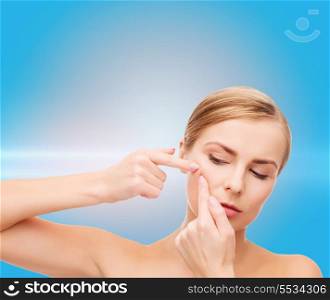 health and beauty concept - face of beautiful young woman squeezing acne spots