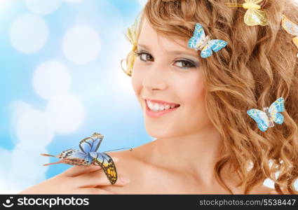 health and beauty concept - happy teenage girl with butterflies in hair and one sitting on her hand