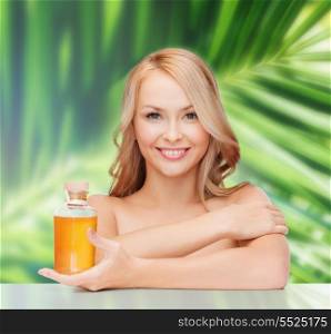 health and beauty concept - happy woman with oil bottle