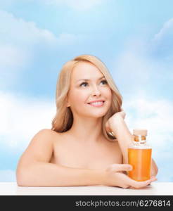 health and beauty concept - happy woman with oil bottle