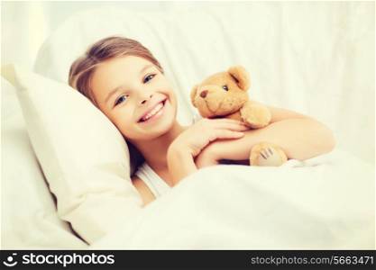 health and beauty concept - little girl with teddy bear sleeping at home