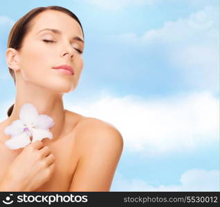 health and beauty concept - relaxed woman with orhid flower and closed eyes