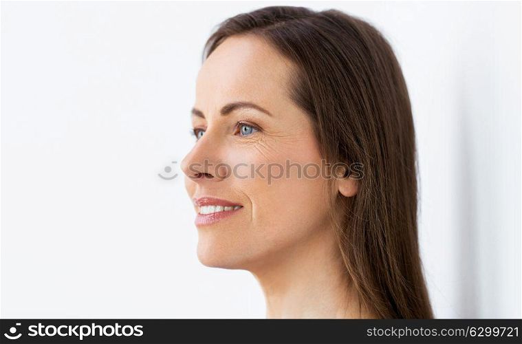 health and beauty concept - side view of happy smiling middle aged woman face. face of happy smiling middle aged woman