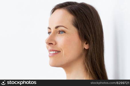 health and beauty concept - side view of happy smiling middle aged woman face. face of happy smiling middle aged woman