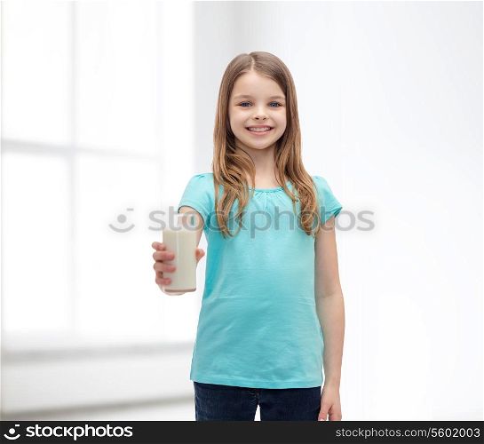 health and beauty concept - smiling little girl giving glass of milk
