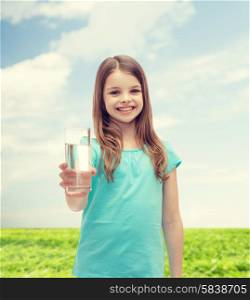 health and beauty concept - smiling little girl giving glass of water