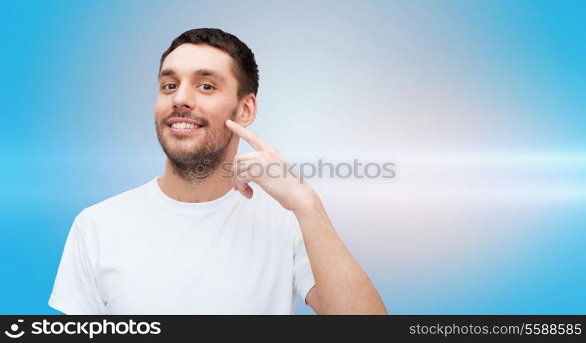 health and beauty concept - smiling young handsome man pointing to cheek