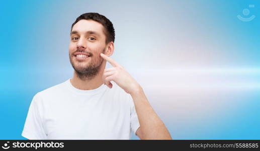 health and beauty concept - smiling young handsome man pointing to cheek