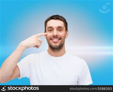 health and beauty concept - smiling young handsome man pointing to eyes