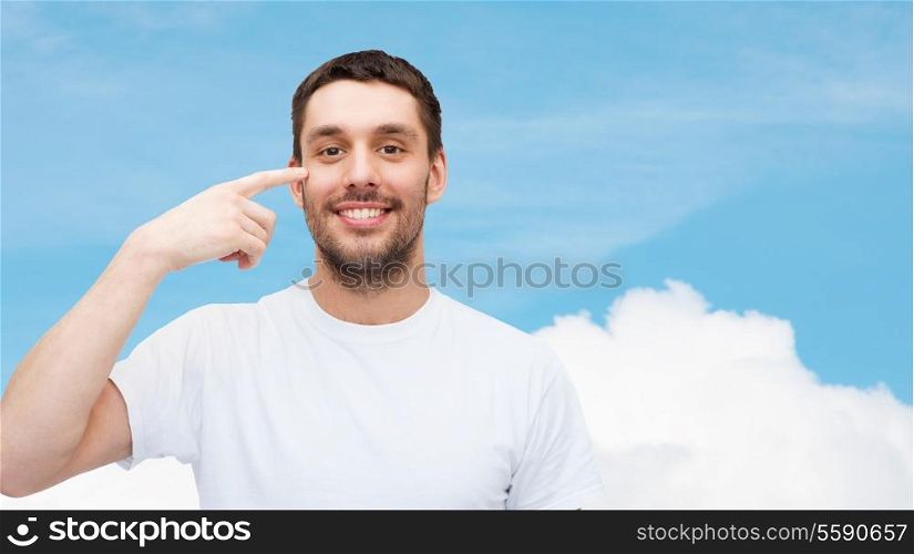 health and beauty concept - smiling young handsome man pointing to eyes