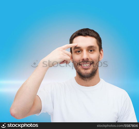 health and beauty concept - smiling young handsome man pointing to forehead