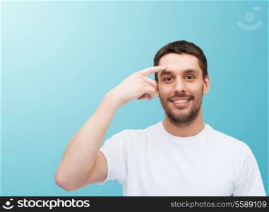 health and beauty concept - smiling young handsome man pointing to forehead