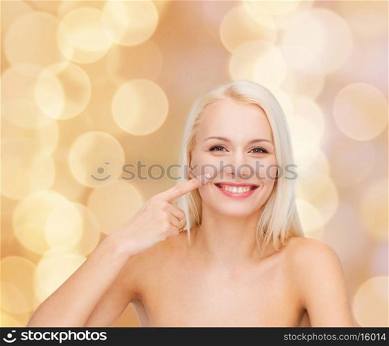 health and beauty concept - smiling young woman pointing to her nose