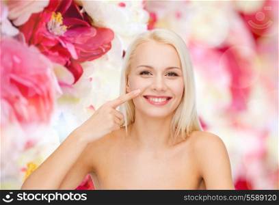 health and beauty concept - smiling young woman pointing to her nose