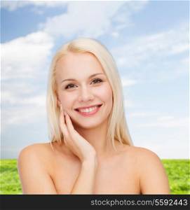 health and beauty concept - smiling young woman touching her face skin