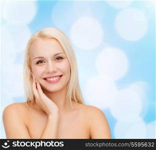 health and beauty concept - smiling young woman touching her face skin