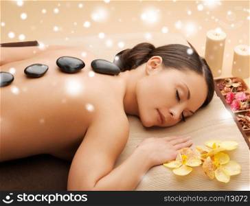 health and beauty concept - woman in spa salon with hot stones