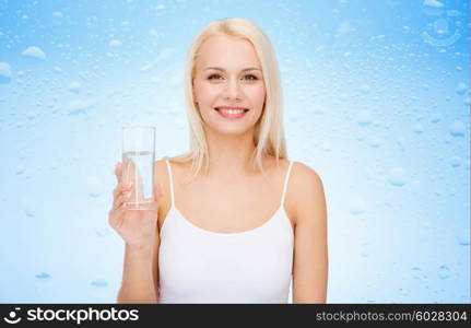 health and beauty concept - young smiling woman with glass of water over drops on blue background. young smiling woman with glass of water