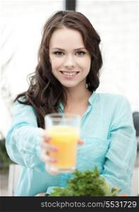 health and beauty concept - young woman holding glass of orange juice