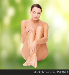 health and beauty, eco, bio, nature concept - beautiful naked woman touching her legs