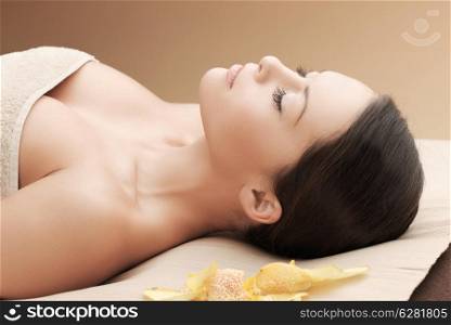 health and beauty, resort and relaxation concept - asian woman in spa salon lying on the massage desk