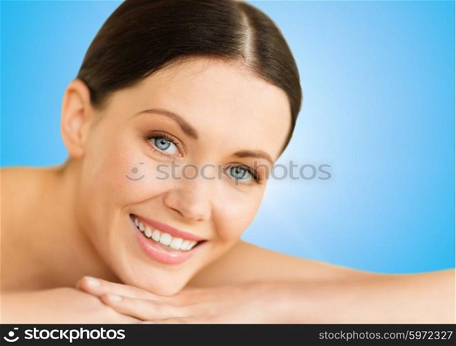 health and beauty, resort and relaxation concept - beautiful smiling woman in spa salon lying on the massage desk
