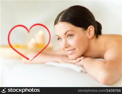 health and beauty, resort and relaxation concept - smiling woman in spa salon lying on the massage desk