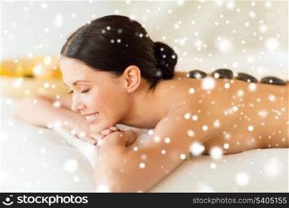health and beauty, resort and relaxation concept - woman in spa salon with hot stones