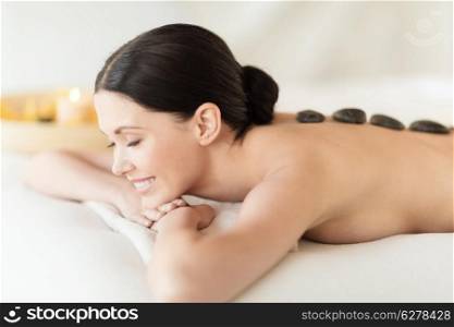 health and beauty, resort and relaxation concept - woman in spa salon with hot stones