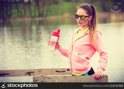 Health and body care idea. Sporty fit attractive woman with bottle of water after exercising workout outdoor on lake shore. woman with water bottle after exercising workout