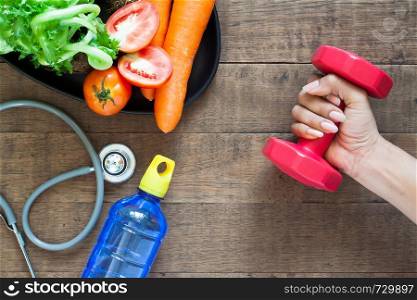 Health and fitness concept. Vegetables, fitness equipment on wooden background