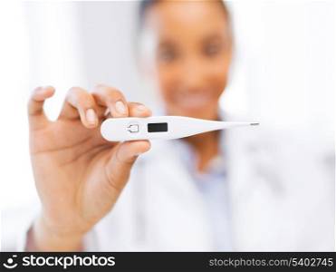health and medicine concept - close up of female doctor holding thermometer