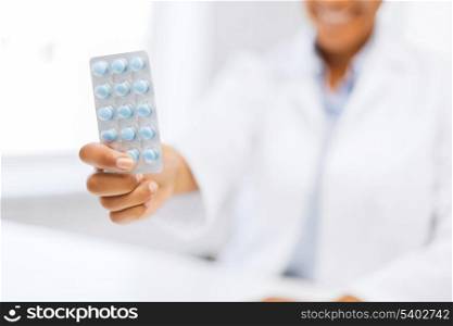 health and medicine concept - female doctor hand giving pack of pills