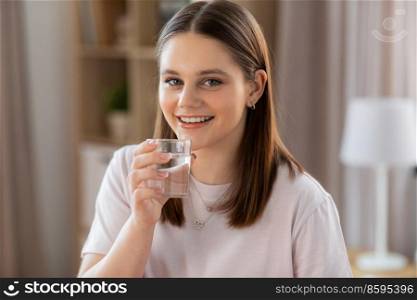 health and people concept - happy smiling girl with glass drinking water at home. smiling girl with glass drinking water at home