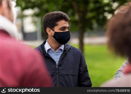 health and people concept - indian man wearing face protective reusable mask for protection from virus disease with friends at park. indian man in reusable mask at park