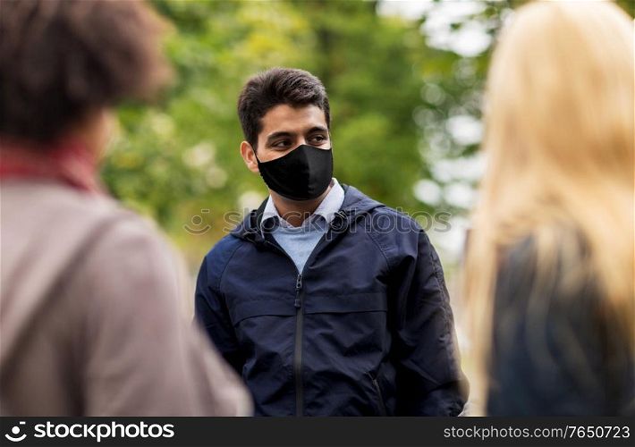 health and people concept - indian man wearing face protective reusable mask for protection from virus disease with friends at park. indian man in reusable mask at park