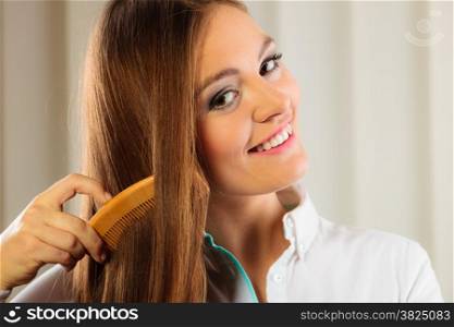 Health beauty and haircare concept - Closeup young business woman refreshing her hairstyle she combing her long brown hair with wooden comb