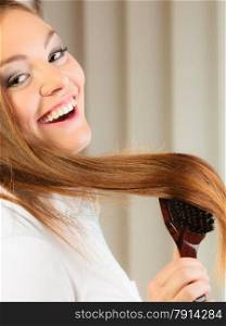 Health beauty and haircare concept - Closeup young business woman refreshing her hairstyle she brushing her long brown hair with wooden brush
